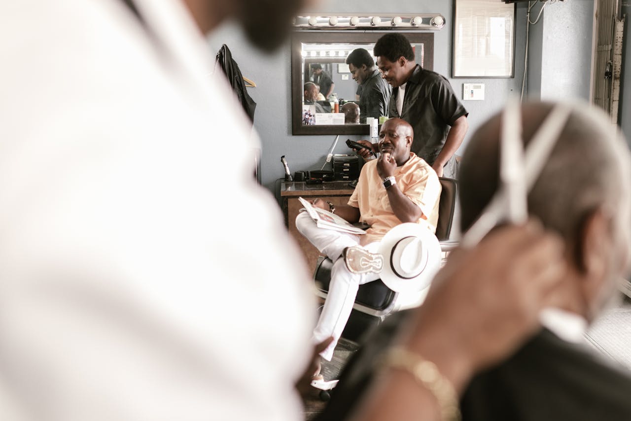 gallery-4 A lively barber shop with clients and barbers engaged, highlighting tools and mirror reflections.