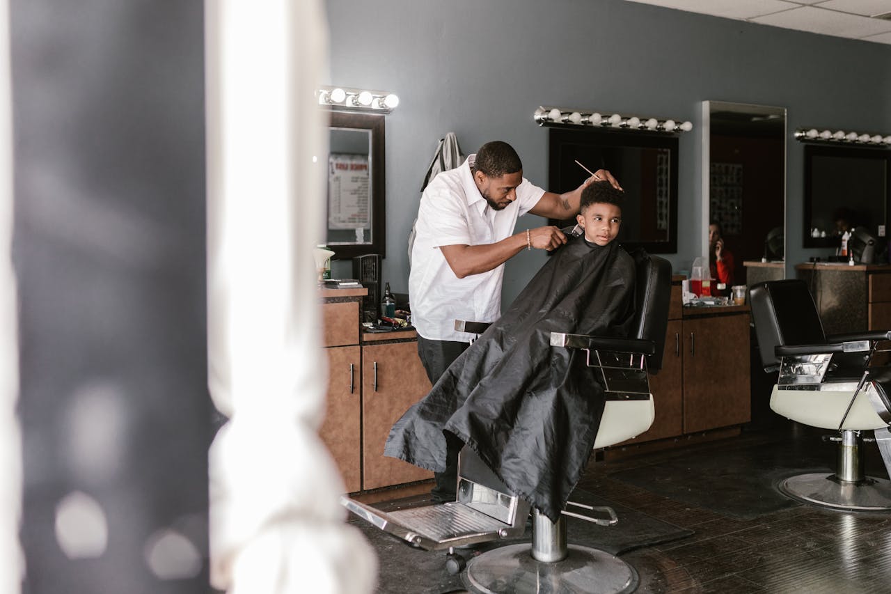 A young boy receiving a haircut in a contemporary barbershop.